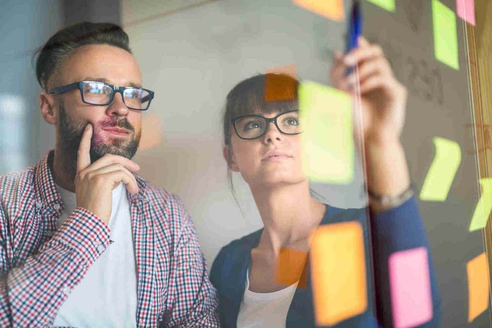 A group of people looking at post-it notes on a board