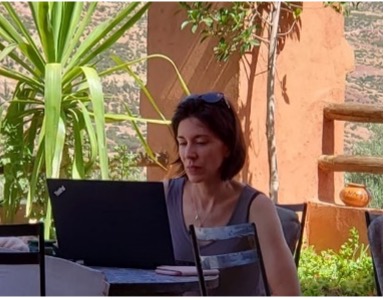 A person sitting at a table with a computer  Description automatically generated